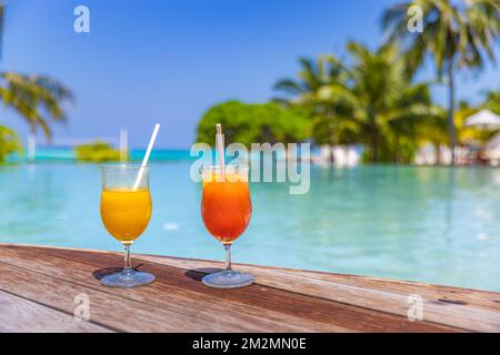 Colorful cocktails served on luxury tropical resort hotel in Maldives. Poolside with blurred palm trees beds umbrellas. Bright sunny pool Stock Photo