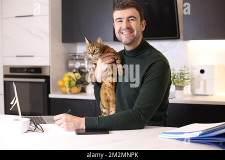 Attractive man working from home with his cat Stock Photo