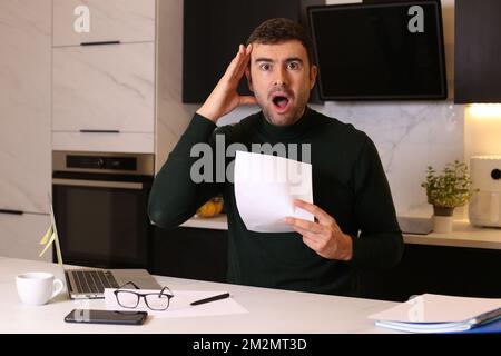 Worried looking man holding document while working from home office Stock Photo