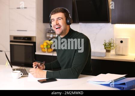 Man in home office talking through headphones Stock Photo