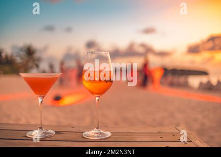 Two cocktail drinks with blur beach and colorful sunset sky in the background. Luxury outdoor leisure lifestyle, relaxing and romantic vibes Stock Photo