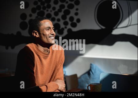 Side view portrait of handsome African young man looking away with positive smiling face. Dramatic portrait. Stock Photo