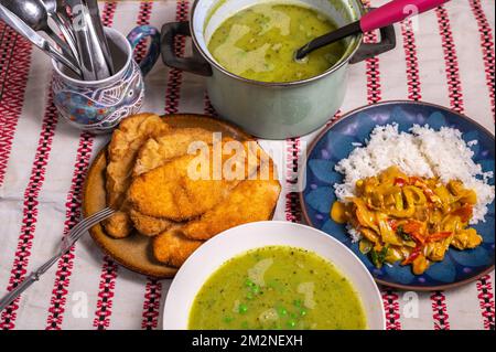 Lunch or dinner table with many meal. Pea soup, breaded fried meat (schnitzel) and asian chicken curry meal with rice. Stock Photo