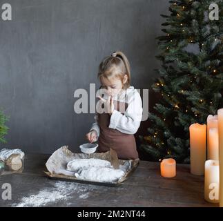 a girl tastes powdered sugar while cooking a Christmas treat Stock Photo