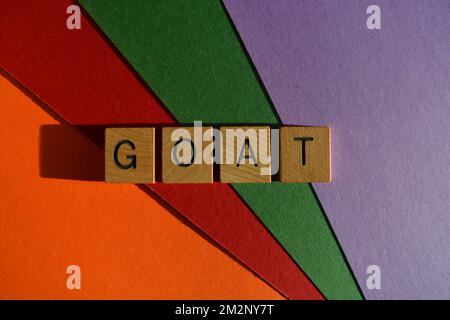 GOAT acronym for Greatest of All Time, in wooden alphabet letters isolated on multicoloured background as banner headline Stock Photo