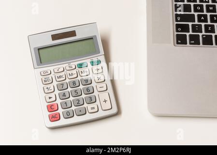 Calculator on Desktop next to Laptop Computer Stock Photo