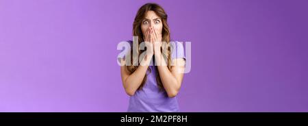 Shocked concerned ambushed scared intense girl gasping hold scream cover mouth stare camera frightened speechless learn terrible bad news stand purple Stock Photo