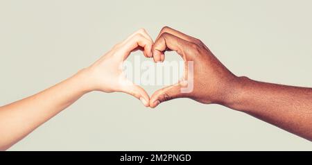 Charity, love and diversity - closeup of female and male hands of different skin color making heart shape Stock Photo