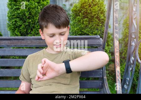An 11-year old teenager looking at the time in his smart watch, a close-up Stock Photo