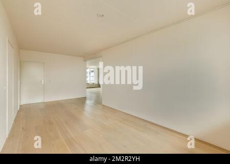 an empty room with wood floors and white walls in the corner, there is no light coming from the window Stock Photo
