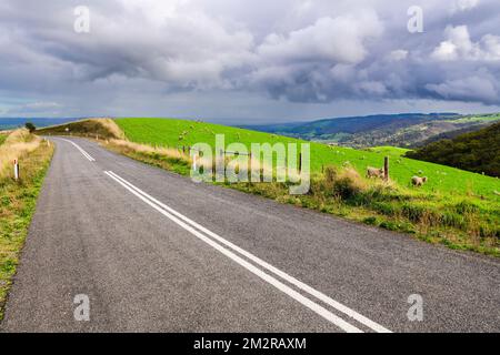 Road through Adelaide Hills farms under stormy clouds during winter season, South Australia Stock Photo