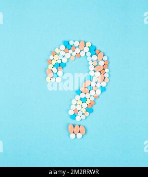 Question mark from laid out of medicine pills on blue background. Stock Photo