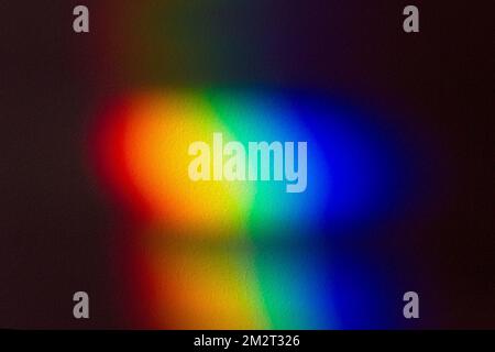 Rainbow color spectrum effect on wall. Light scatter after hitting the glass object on to a dark wall. Stock Photo