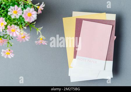 Colorful blank sticky note papers with flower on grey colour background for your text or message. Stock Photo