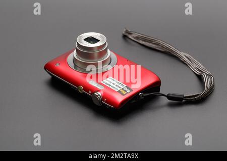Compact red camera with a retractable lens close-up on a gray background. Stock Photo