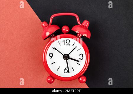 Red vintage alarm clock on red and black colour background. Stock Photo