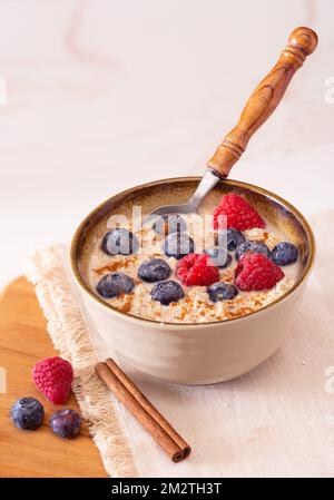 Cooked steel cut oatmeal in a bowl with blueberries, raspberries, and cinnamon Stock Photo