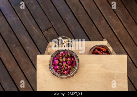 Glass jars with dried flowers, chilli peppers and dehydrated orange slices on a three-step ladder with sinar varnish Stock Photo