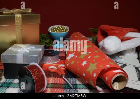 Attributes for Christmas gifts. Colored ribbons, gift boxes, wrapping paper on a wooden table. Preparing for Christmas. Stock Photo