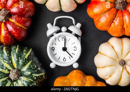 An alarm clock and pumpkins on black table. Stock Photo