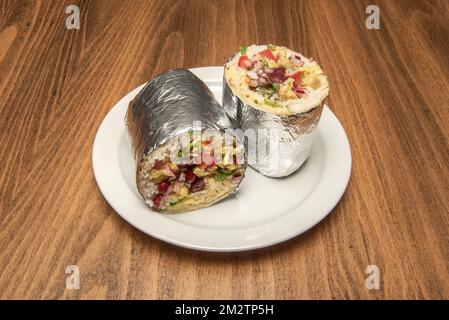 A wonderful burrito stuffed with rice, sautéed vegetables and red beans wrapped in aluminum foil split in half Stock Photo