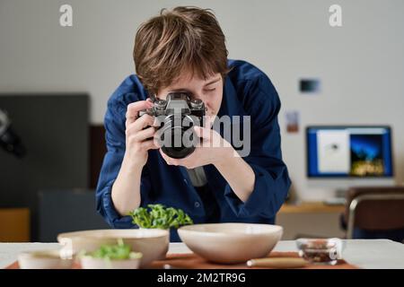 Female photographer using digital camera to take picture of food during her work in studio Stock Photo