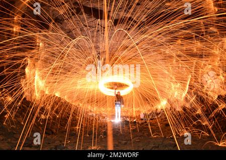 A long exposure shot of a person rotating a burning steel wool in a cave Stock Photo