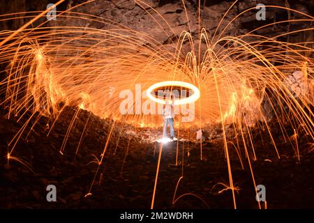 A long exposure shot of a person rotating a burning steel wool in a cave Stock Photo