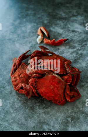 some cooked velvet crabs, also known as necora crabs, on a gray stone surface Stock Photo