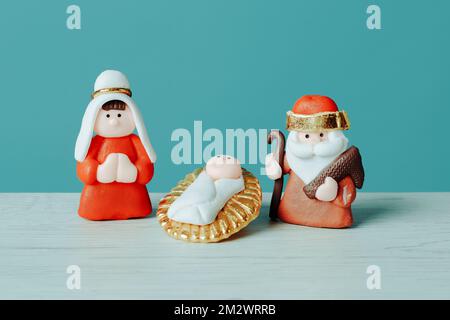 closeup of a childish depiction of the holy family, formed by the child jesus, the virgin mary and saint joseph, on a white surface, against a blue ba Stock Photo