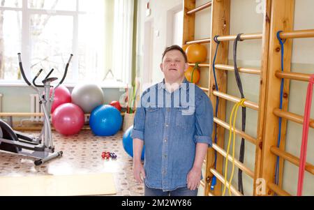 a man with down syndrome is standing in a rehabilitation center. Stock Photo