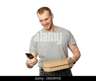 a man holds a phone and a pizza in his hands on a black background.Pizza delivery Stock Photo