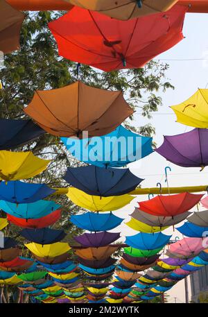 Upside down Multicolored rainbow umbrellas hanging above as street art. Colorful View. Stock Photo