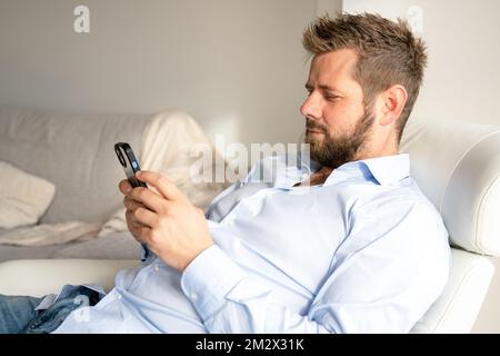 Young handsome man at home using smartphone Stock Photo