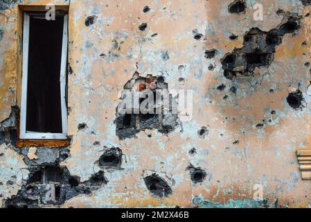 KHARKIV REGION, UKRAINE - DECEMBER 13, 2022 - Traces of Russian shelling on the wall of a house in the liberated city of Izium, Kharkiv Region, northeastern Ukraine. Stock Photo
