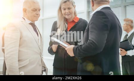 close up . group of employees standing near the office window. communication of partners against the background of sunset Stock Photo