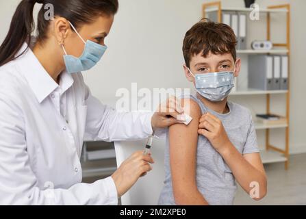 Nurse or doctor giving injection to little school boy to protect him from infection Stock Photo