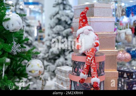 Christmas long-legged gnome in a suit with a scandinavian ornament on the background of boxes with gifts. Stock Photo