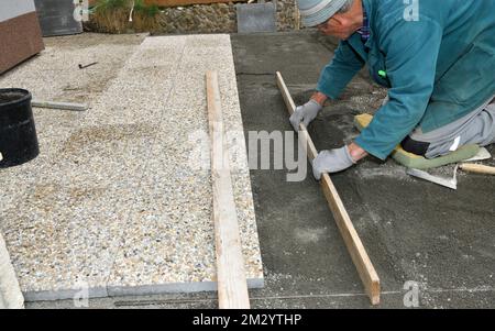 The bricklayer levels the floor using a spirit level and sand before laying tiles Stock Photo