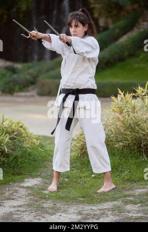 Young karate woman in fighting stance holding a pair of sai outdoors. High quality photo Stock Photo