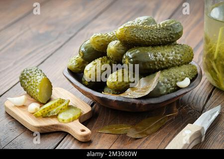 Pickled cucumbers in a bowl. Marinated cucumber slices on a cutting board. Homemade pickles, vegetable canning. Stock Photo