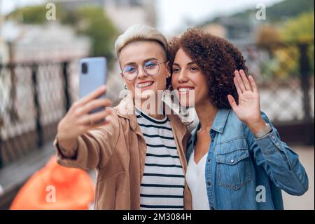 Two attractive joyous ladies taking a selfie on the veranda Stock Photo