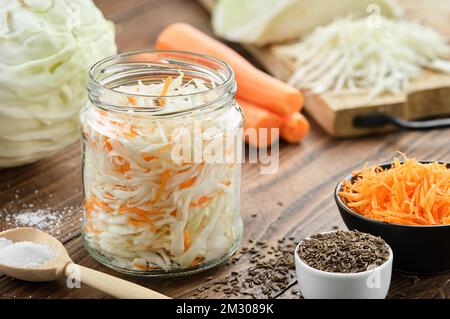 Chopped cabbage in a jar for making pickled sauerkraut. Cooking of homemade sour cabbage. Fermented product, coleslaw salad. Healthy food, diet food. Stock Photo
