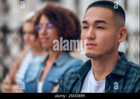 Cute pensive young man in the company of women Stock Photo
