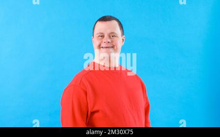 a man with down syndrome on an isolated blue background. Stock Photo