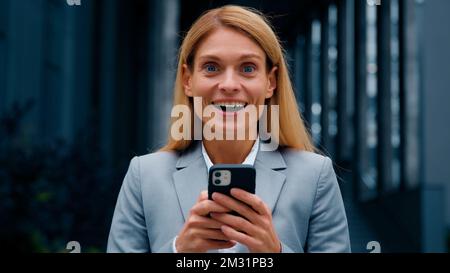 Close-up enthusiastic happy businesswoman receiving notification reading good news on telephone surprised excited woman saying wow winning lottery Stock Photo