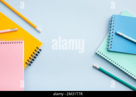 colored notebooks, colored pencils on a light table. Place for your text. High quality photo Stock Photo