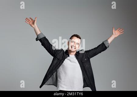 amazed man celebrating victory on gray background. Stock Photo