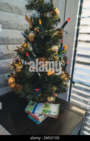 under a christmas tree lies a bundle of cash Stock Photo