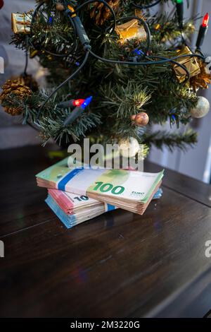 under a christmas tree lies a bundle of cash Stock Photo